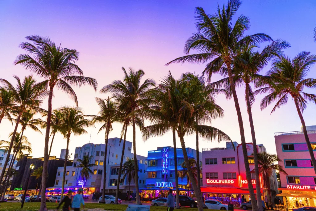 Colorful Miami Beach street with palm trees at sunset.