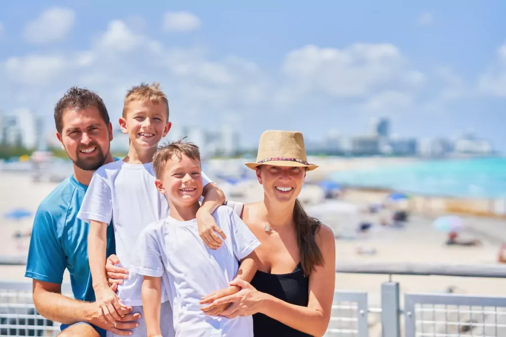 Family smiling on a sunny beach day.